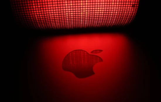 Apple logo reflecting red light under mesh pattern.