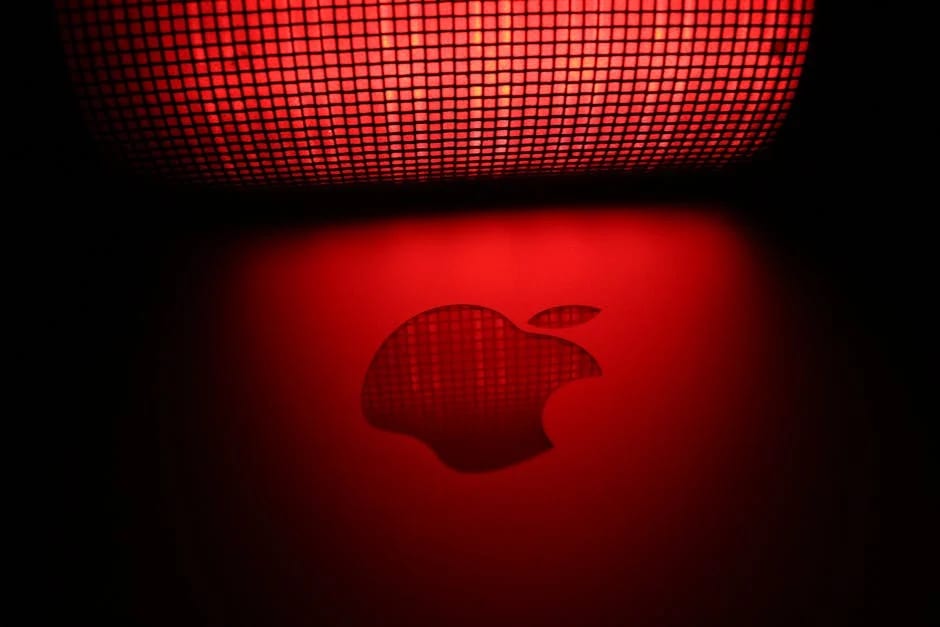 Apple logo reflecting red light under mesh pattern.