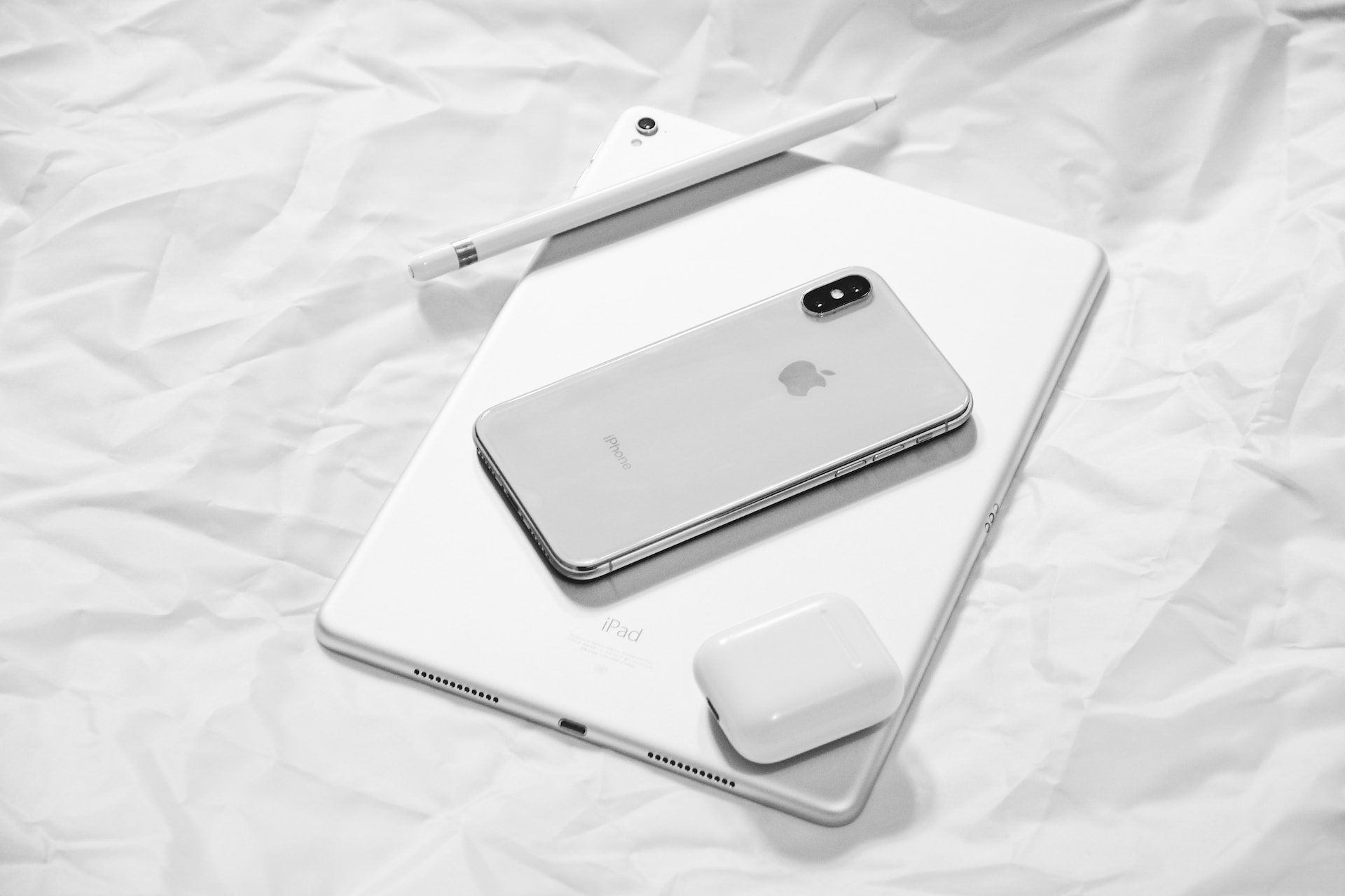 Apple Pencil, iPhone X and AirPods resting on an iPad.